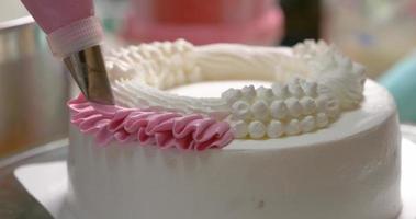 Close-up top view The chef is squeezing the cream into a flower shape on the top of the cake. video