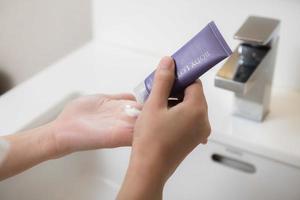 Close up of women applying body lotion cream on hand. photo