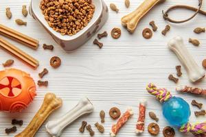 A bowl with dog food, dog treats and toys on a wooden floor. photo