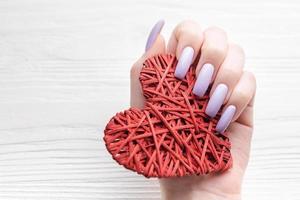 Girl's hands with delicate purple manicure and decoratine heart photo