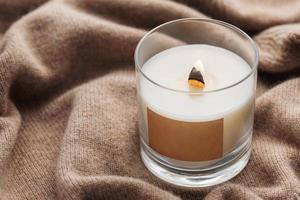 A candle burns on the background of a knitted sweater. photo