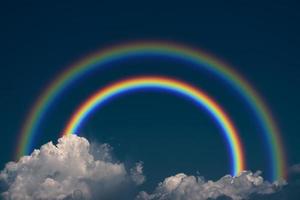 Primary rainbow and secondary rainbow back dark cloud on the sky