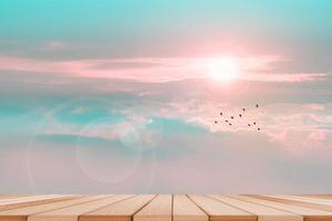 mesa de madera y amanecer y cielo de horizonte con nubes de tono azul pastel y niebla en la cima de la montaña con pájaros volando foto