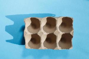 Empty eggs carton box with hard shadows on blue background. photo