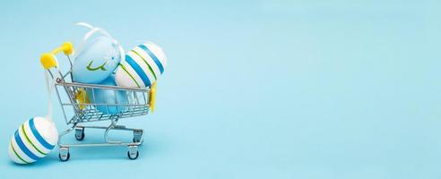 Easter eggs in the shopping cart on a blue background. banner photo