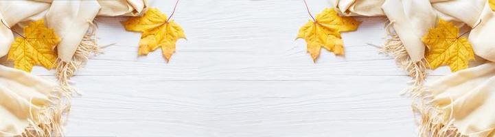 hojas de otoño con una bufanda sobre un fondo de madera con espacio para copiar. bandera foto