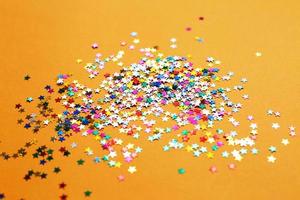 multicolor sparkles on a orange background. Festive backdrop for your projects. photo