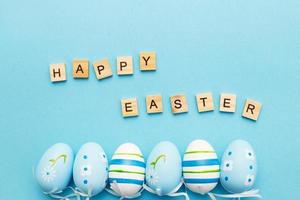 inscription happy easter with colorful handmade painted eggs on blue background photo