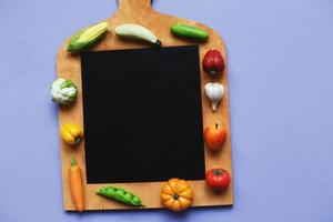 vegetables and fruits on the cutting board on purple background. healthy cooking concept photo