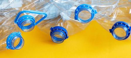 a lot of plastic empty rumpled used bottles on a yellow background. waste and pollution concept photo
