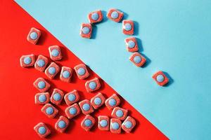 capsules for kitchen dishwashers and a question mark on a blue and red background. flat lay. photo