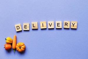 inscription delivery with vegetables and fruits on purple background. delivery service concept photo