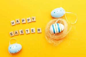 colorful handmade painted eggs in the nest on orange background photo