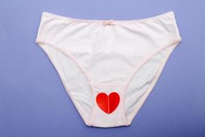 pink women's briefs with a heart on a purple background. hygiene and women's health care concept photo