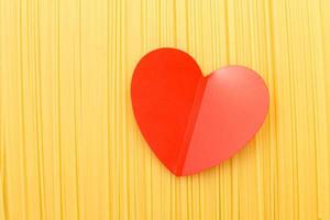 spaghetti yellow background with a red heart close. raw pasta macro photo