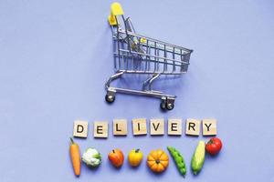 Shopping cart vegetables and fruits on purple background. delivery service concept photo