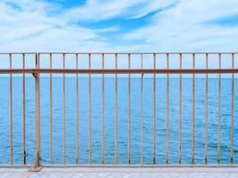 View on a clear blue sea under the cloudy sky through a fencing of a breakwater photo