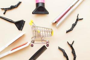 various hairdressing tools with shopping cart on a beige background. beauty salon concept photo