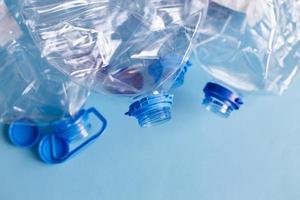 a lot of plastic empty rumpled used bottles on a blue background. waste and pollution concept photo
