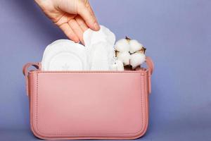mano de mujer saca panty liner de bolsa de cosméticos rosa con tampones y toallas sanitarias femeninas foto