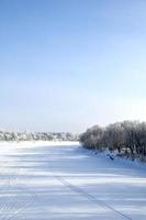 a frozen river lined with frost covered trees photo