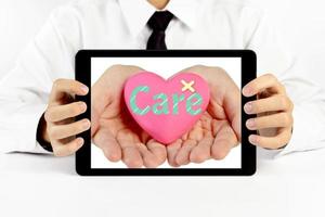 Businessman holding a tablet with heart and write the word care photo