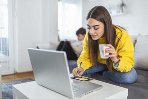 mujer joven ocupada con hijo en casa. foto de un niño jugando mientras su madre está trabajando en una computadora. joven madre con un niño pequeño trabajando en la computadora desde casa