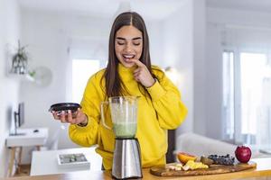 Healthy woman enjoy making green vegetables detox cleanse and green fruit smoothie with blender in kitchen at home. Healthy lifestyle. Beautiful girl tasting smoothie photo