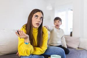 Tired mother trying to work on a laptop at home during her kid crying. Childcare and working mom concept. Women powerful. Toddler tantrum. Young lady working at home during quarantine. photo