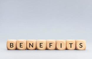 Benefits word on wooden blocks on gray background. Copy space photo