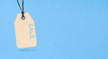 Sale Price tag with text cut out on cardboard isolated on blue background. Copy space photo