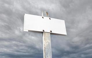 Blank white aged sign on stormy sky background. Weathered metallic post sign. Template Mock up photo