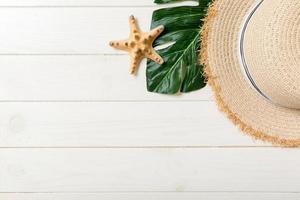 Straw hat, green leaf and starfish On a white wooden background. top view summer holiday concept with copy space photo