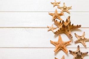 Summertime wooden table with starfish and seashells on a white background top view. Copy space background, summer concept photo