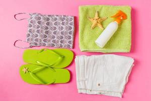 Flat lay composition with green Beach accessories on pink or coral color background. Summer holiday background. Vacation and travel items top view photo