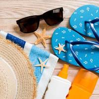 flip flops, straw hat, starfish, sunscreen bottle, body lotion spray on wooden background top view . flat lay summer beach sea accessories background, holiday concept photo