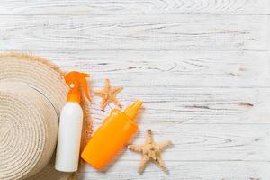 Sunscreen bottles with starfish and sunhat on white wooden table with copy space. Travel healthcare accessories top view photo