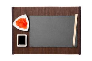 Empty rectangular black slate plate with chopsticks for sushi, ginger and soy sauce on background. Top view with copy space for you design photo