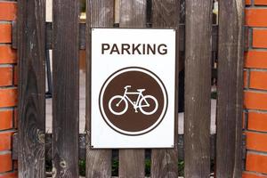 A parking place for bicycles, a sign on a wooden fence photo