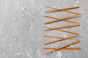 Many bamboo chopsticks on black cement stone background, top view with copy space. a lot of sushi sticks in the form of an ornament photo