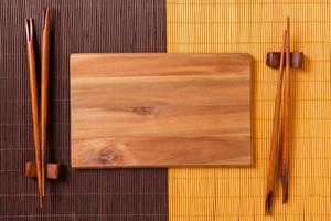 Empty rectangular wooden plate with chopsticks for sushi and soy sauce on wood background. Top view with copy space photo
