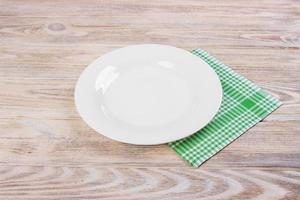 plato blanco vacío sobre mesa de madera, servilleta verde foto