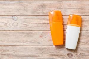 Two Sunscreen bottles on a bright wooden background, top view with copy space photo