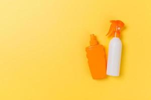 flat lay concept of summer travel vacation. Sunscreen bottle mock up on yellow background top view with copy space photo