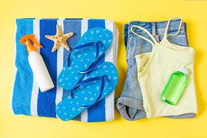 Flat lay composition with blue Beach accessories on yellow color background. Summer holiday background. Vacation and travel items top view photo