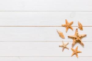 endecha plana de varias conchas marinas y estrellas de mar sobre una mesa de madera blanca, vista superior. copie el fondo del espacio, el concepto de verano foto