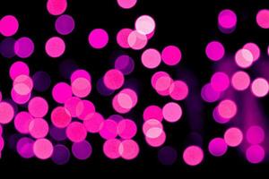 Unfocused abstract purple bokeh on black background. defocused and blurred many round light photo