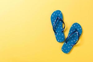 Blue flip flops on yelow Background. Top view with copy space photo