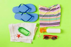 Flat lay composition with Beach accessories on green color background. Summer holiday background. Vacation and travel items top view photo