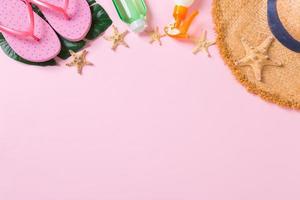 accesorios de playa con sombrero de paja, botella de protección solar y estrella de mar en la vista superior de fondo rosa con espacio para copiar foto